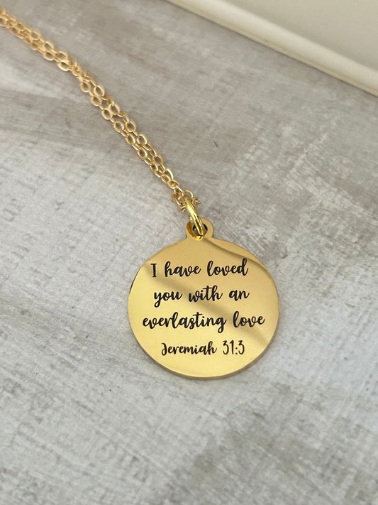 May include: A gold necklace with a round pendant that reads &#39;I have loved you with an everlasting love Jeremiah 31:3&#39;.